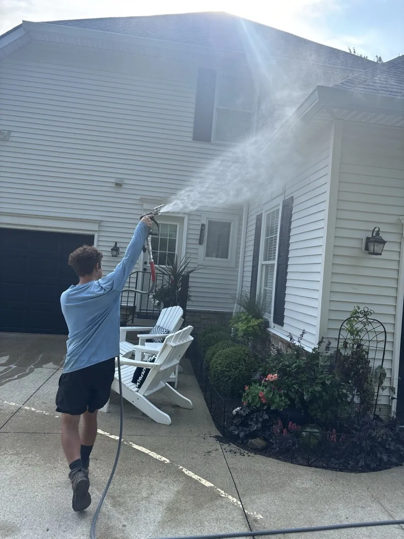 Soft wash spray reaching the second-floor siding