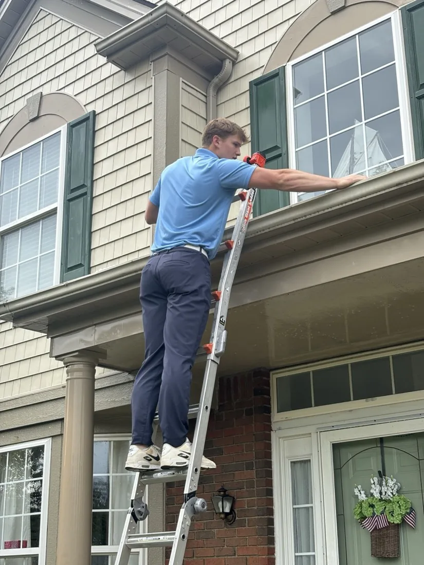 Window cleaning seen from the driveway, ladder to the porch roof