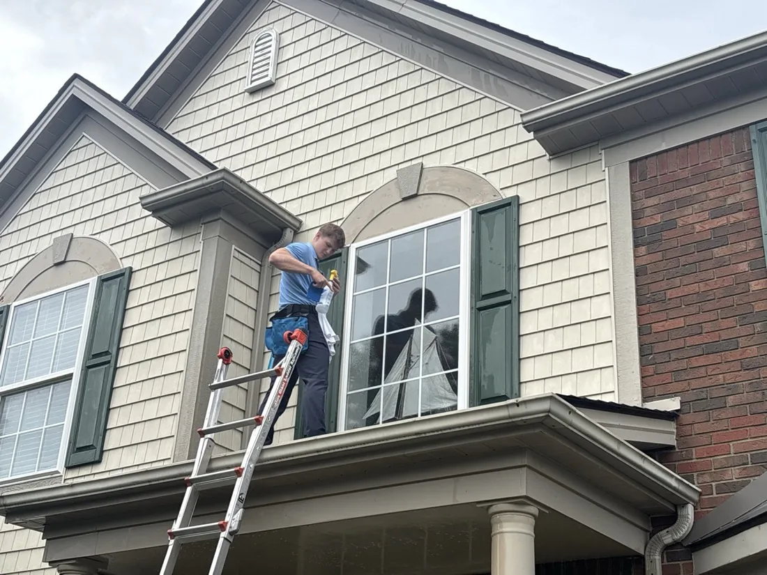 Cleaning an upper-floor window from a ladder