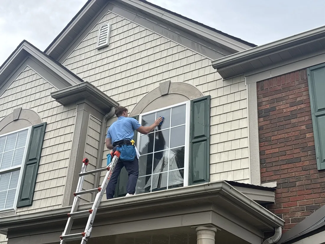 Squeegeeing a soaped arched window above the front porch