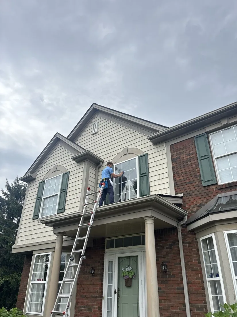 Carrying the ladder along the front of the house between windows