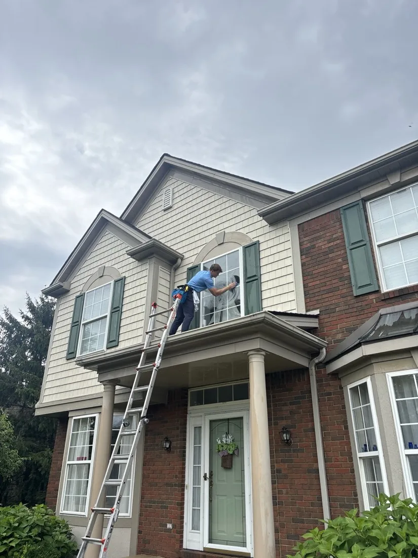 Ladder set beside the front entry while an upper window is cleaned