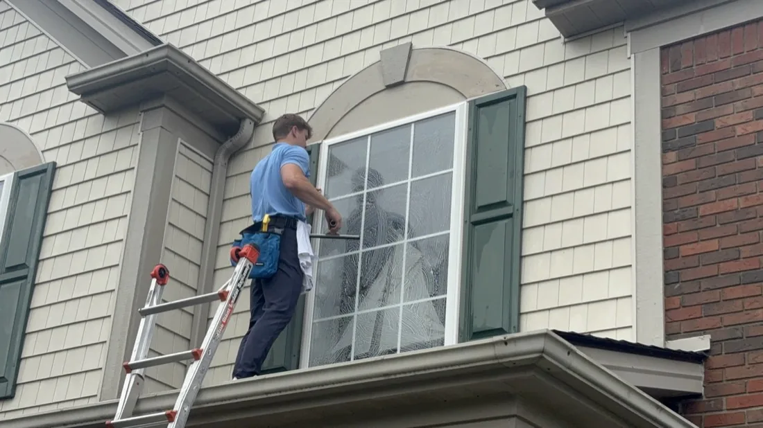 Wiping down the frame of an upper-floor arched window