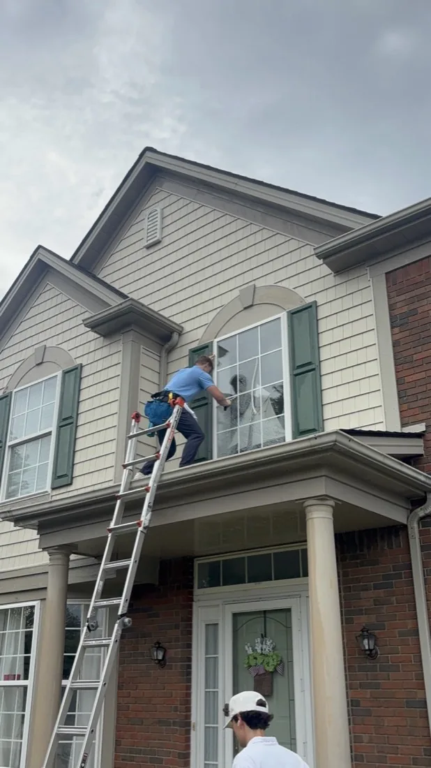 Second technician steadying the ladder at the porch roof