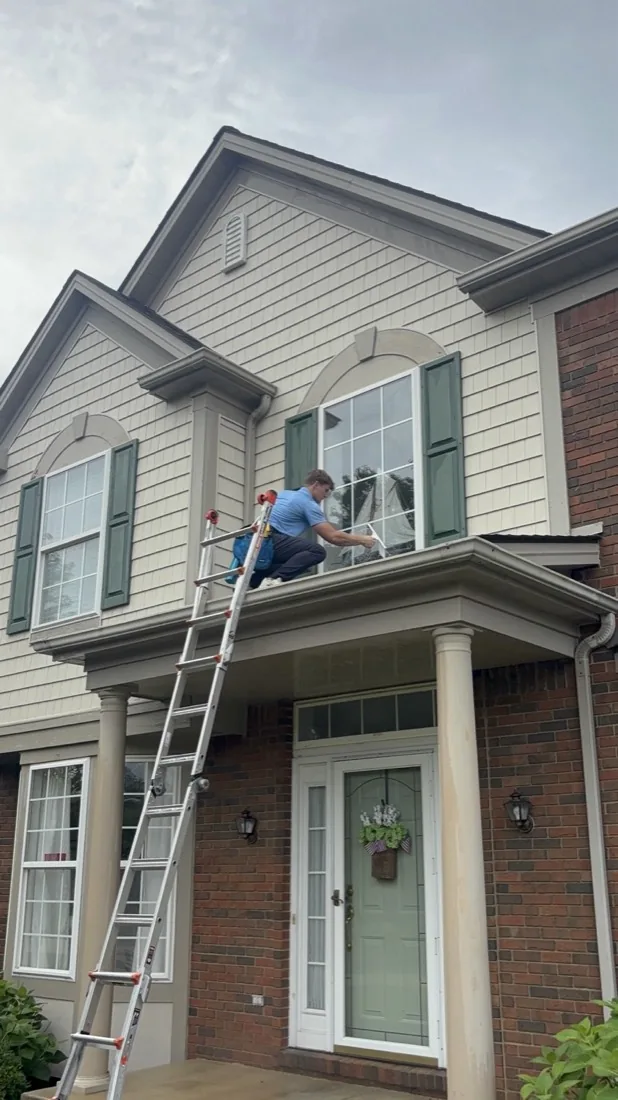 Upper-floor window cleaning above a brick and shake front